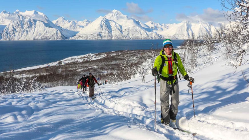 Auf Skitour in den Lyngen Alpen steigt Bergführer Michael Rüter in grüner Jacke den verschneiten Hang hinauf.