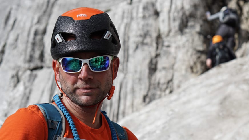 Guide Markus Schubert trägt schwarzen Petzl-Kletterhelm mit weißer Sonnenbrille und hält blaues geflochtenes Seil am Gurt.