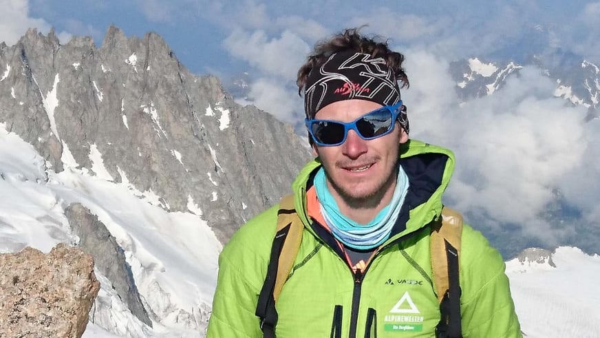 Bergführer Christoph Sokoll trägt grüne Softshelljacke mit Alpine Welten Logo vor Gletscherlandschaft im Hochgebirge.