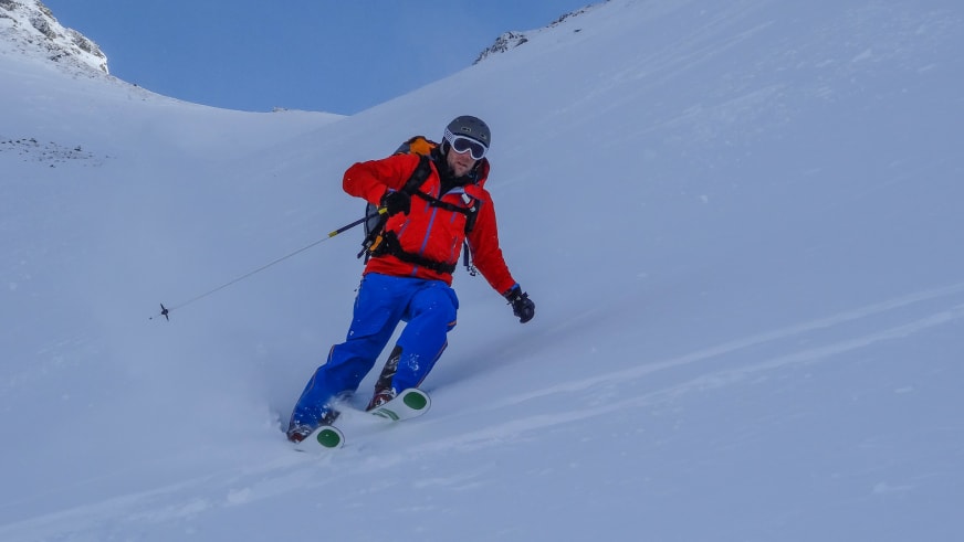 Bei einer Skitour fährt Bergführer Andreas Wiedenmann durch unberührten Tiefschnee einen steilen Hang hinab.