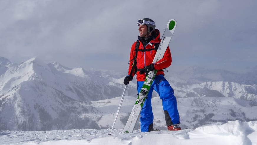 Bergführer Andreas Wiedenmann steht mit Skiern auf einem schneebedeckten Gipfel und blickt über die Berglandschaft.