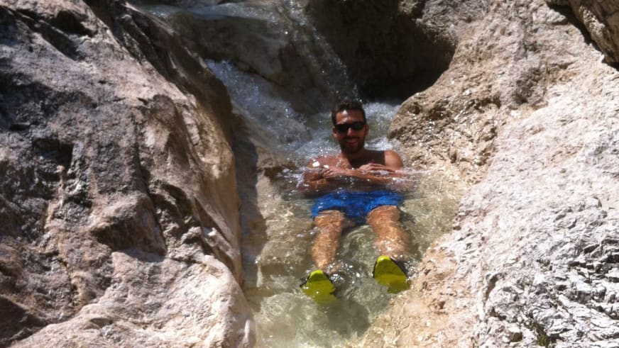 Im kristallklaren Felsbecken badet Bergführer Rene Hellmann mit gelben Schwimmflossen und Sonnenbrille bei Sommerwetter.