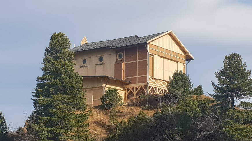 Das Schachenhaus zeigt seine charakteristische Holzfassade mit verglastem Wintergarten und Terrasse im dichten Bergwald.