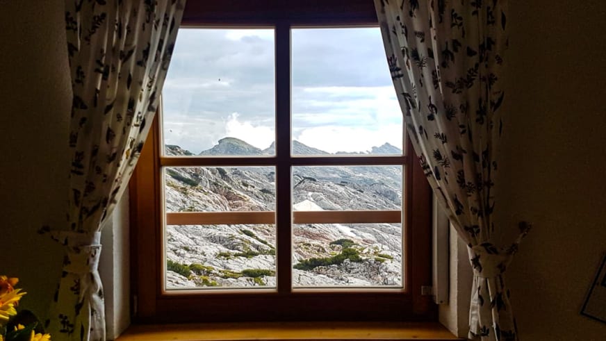 Blick durch das Fenster des Ingolstädter Haus auf die umliegende Berglandschaft mit kahlen Felswänden.