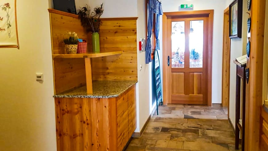Empfangsbereich im Ingolstädter Haus mit Holztheke und Natursteinboden im alpinen Eingangsbereich.