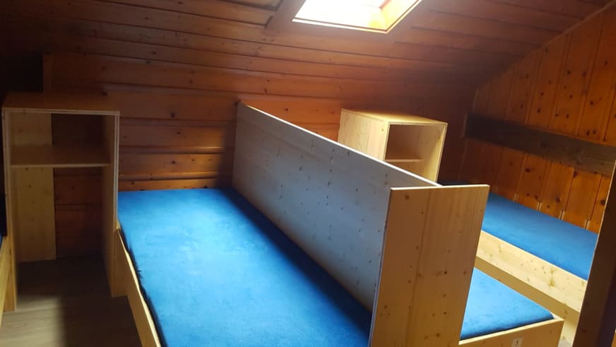 Matratzenlager im Ingolstädter Haus mit Etagenbetten aus Holz und blauen Matratzen unter der Dachschräge.