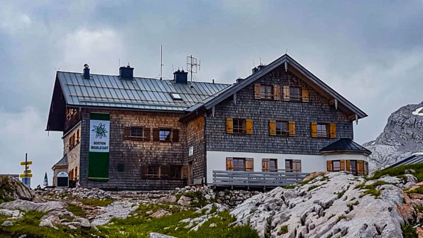 Außenansicht des Ingolstädter Haus mit Holzschindelfassade und grünem Dach auf Kalksteinplateau.