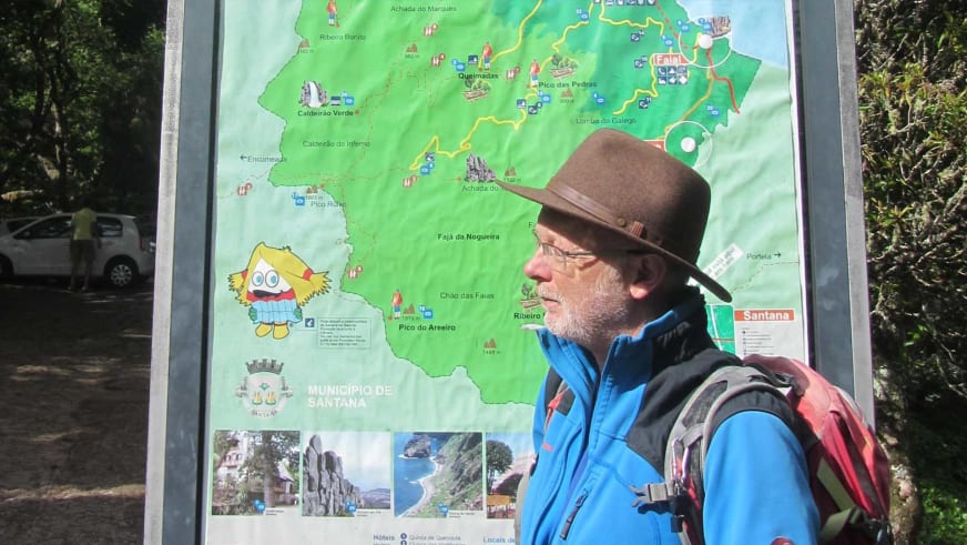 Portrait von Bergwanderführer Werner Neubauer mit grauem Bart vor Wanderkarte, er trägt braunen Hut und blaue Softshelljacke.