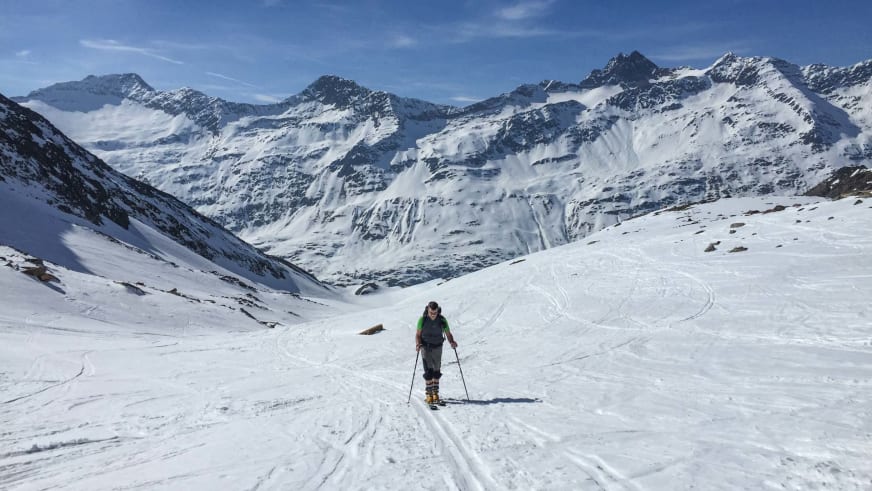 Bergwanderführer Michael Lichtenstern steht mit Tourenskiern und grüner Jacke in einem hochalpinen Schneekar.