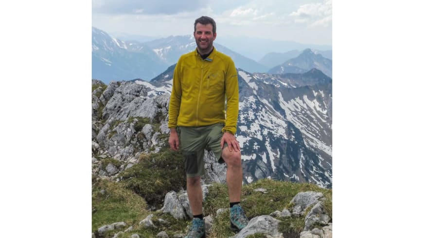 In gelber Softshelljacke steht Bergwanderführer Michael Lichtenstern entspannt auf einem Felsblock in den Hohen Tauern.
