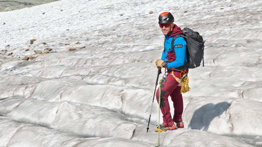 Bergführer Julian Conrad steht mit Helm, Steigeisen und gelbem Seil auf einem zerklüfteten Gletscher bei hellem Tageslicht.