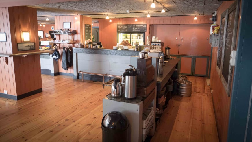 Gastraum mit grauem Tresen und Espressomaschine im Hotel Finse 1222 zeigt rustikale Holzvertäfelung.
