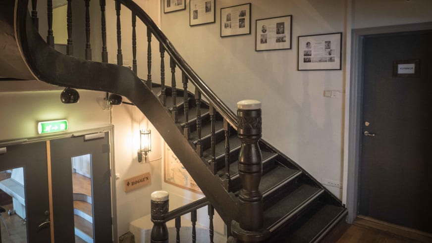 Geschwungene Holztreppe mit gedrechselten Balustern im Hotel Finse 1222 führt vom Eingangsbereich nach oben.