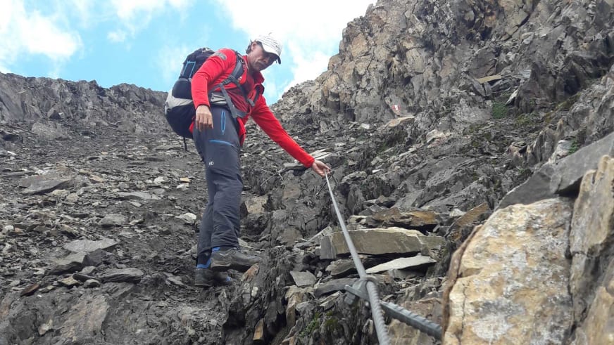 Über Geröll und Felsbrocken steigt Bergwanderführer Thomas Schill in roter Jacke durch eine Kalksteinrinne.