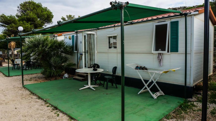 Mobilheim mit weißer Holzverkleidung und grünen Fensterläden im El Bahira Camping Village (San Vito lo Capo) mit überdac