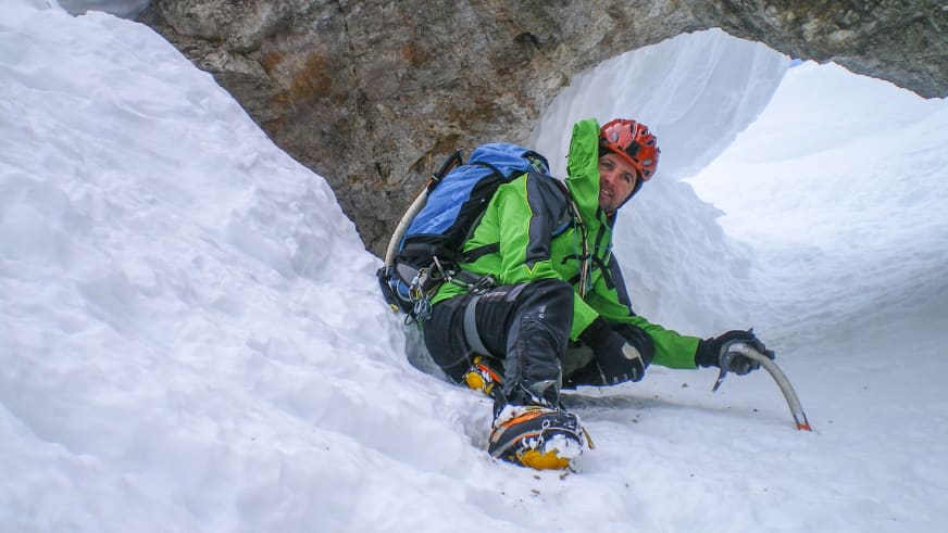 Bergführer Markus Hofmann sitzt entspannt in einer verschneiten Gletscherspalte mit rotem Helm und Eispickel.