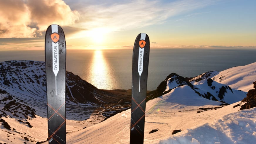 Bergführer Hubert Walther führt Skitouren in Island durch. Zwei Dynastar-Tourenski stehen im Schnee vor verschneiter Fjordlandschaft bei goldenem Abendlicht.