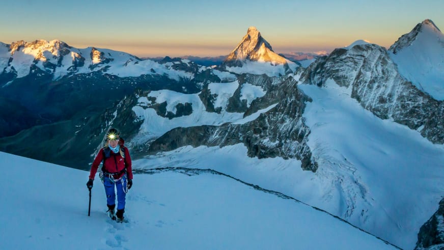 Bergwanderführerin Maria Müller steigt mit Helm, Eispickel und Steigeisen über spaltenreichen Gletscherboden auf.
