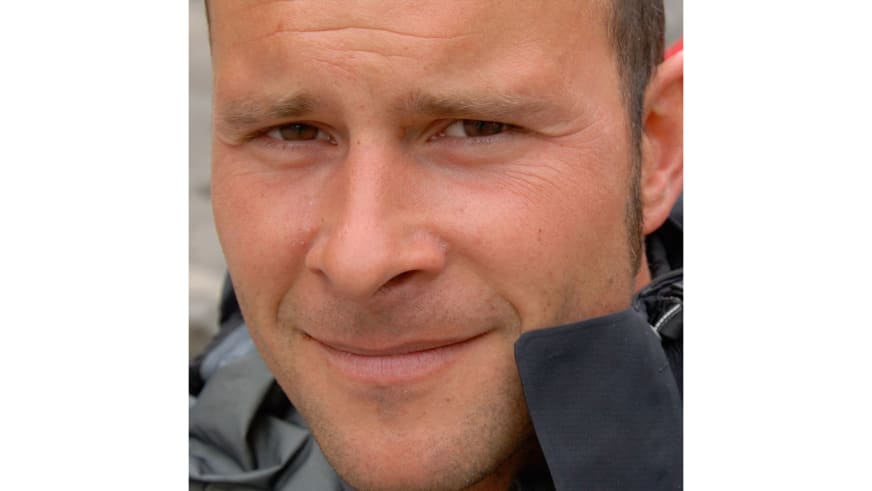 Bergführer Uwe Berg lächelt in die Kamera und trägt dunkle technische Outdoor-Jacke bei Tageslicht.