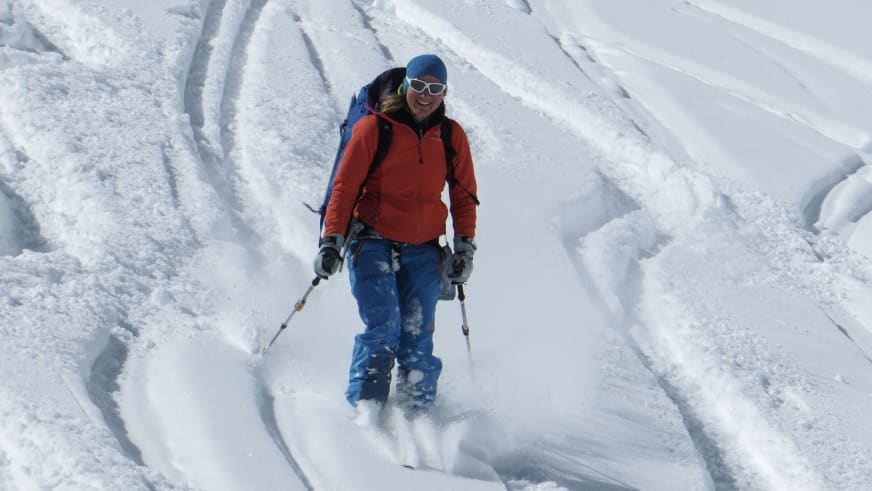 Durch tiefen Pulverschnee auf einem Gletscher stapft Bergwanderführerin Karin Toni Bigel zwischen deutlich sichtbaren Gletscherspalten.