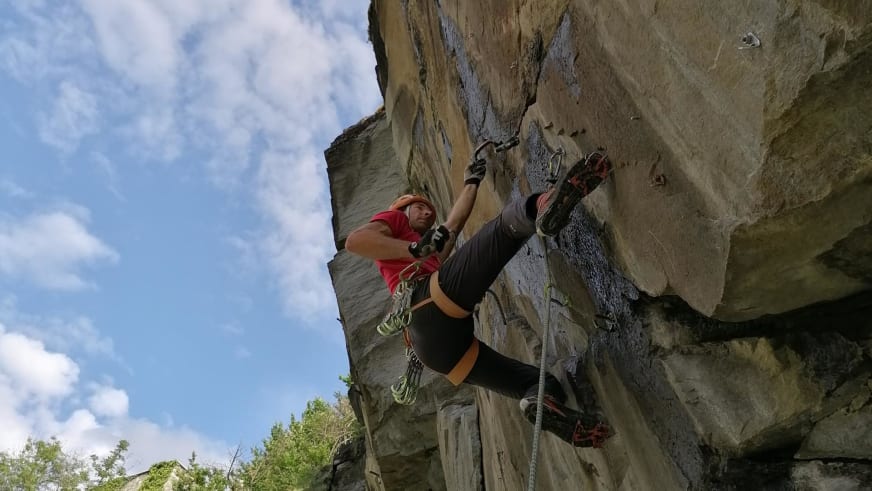 An einer steilen Kalksteinwand klettert Bergführer Rolando Varesco im roten Shirt, während eine zweite Person im Hintergrund folgt.