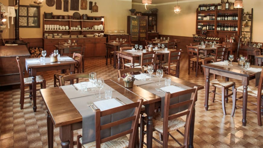 Restaurant der Pensione Ceaglio mit eingedeckten Holztischen, Weingläsern und traditioneller alpiner Ausstattung.