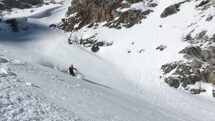 Auf Skiern fährt Bergführer Matthias Hahn einen steilen schneebedeckten Hang hinab und wirbelt dabei Schneepulver auf.