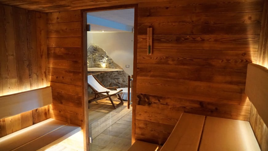 Sauna der Pensione Ceaglio mit Fichtenholz-Verkleidung, zweistufigen Bänken und LED-Beleuchtung im Wellnessbereich.