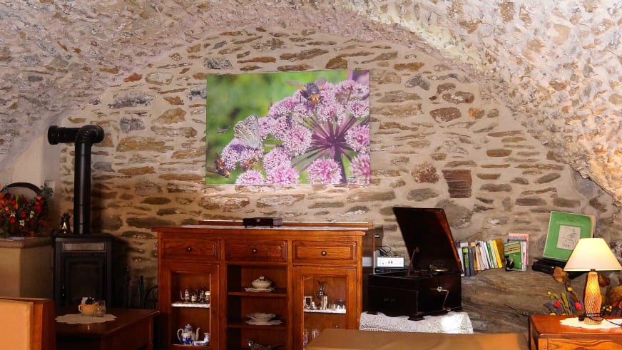 Taverne im Hotel Ceaglio zeigt eine Natursteinwand, Holzkommode mit Geschirr und gusseisernen Kaminofen.