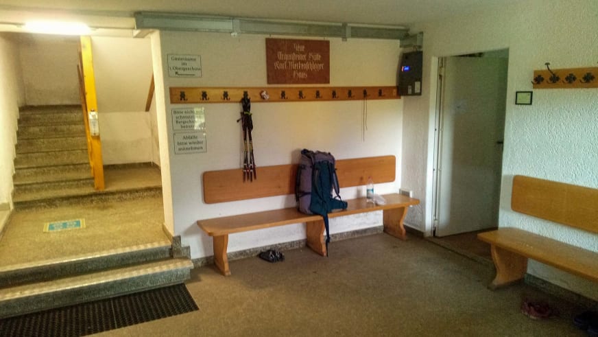 Eingangsbereich der Traunsteiner Hütte mit Garderobe, Holzbank und Aufbewahrungsmöglichkeiten für Wanderausrüstung.