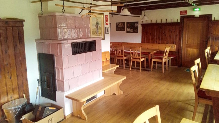 Gemütlicher Gastraum in der Traunsteiner Hütte mit traditionellem Kachelofen und Holzeinrichtung.