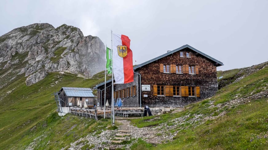 Die Nördlinger Hütte in Holzbauweise mit Solarpanels und österreichischen Fahnen auf der Almwiese.
