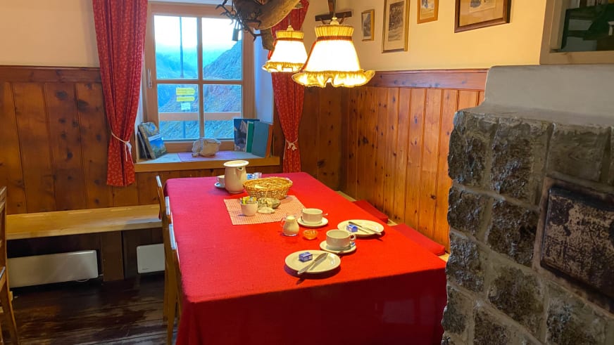 Traditioneller Gastraum der Richterhütte mit Holzvertäfelung, gedecktem Tisch und Kachelofen.