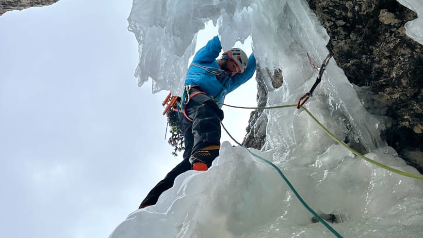 Bergführer Thomas Scherzer klettert mit Eispickel durch eine natürliche Öffnung in der blauen Eiswand.