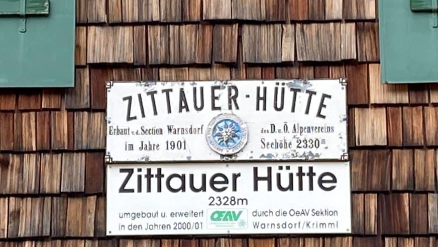 Historisches und modernes Hüttenschild der Zittauer Hütte an Holzschindel-Fassade mit Höhenangabe 2328 m.