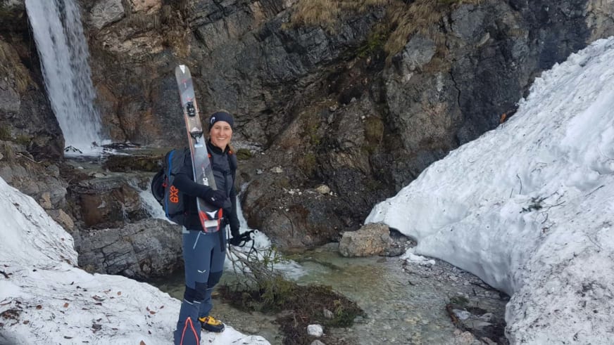 Mit Ski in der Hand steht Bergwanderführerin Elisabeth Götzinger auf Schnee zwischen Felswänden.
