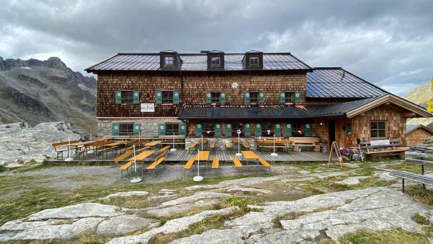 Sonnenterrasse der Zittauer Hütte mit 15 gelben Liegestühlen und Biergarnituren vor der Holzschindel-Fassade.