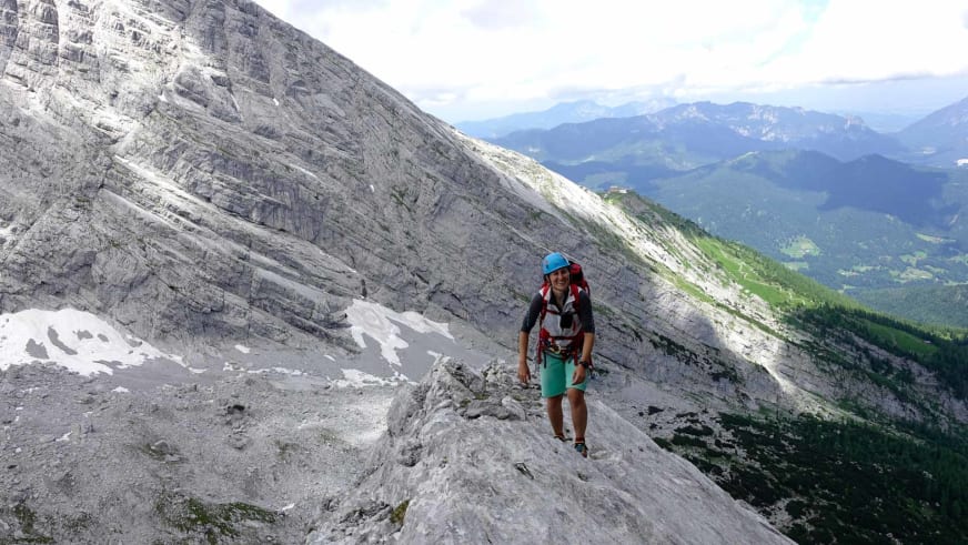 Elisabeth Götzinger als Bergwanderführerin mit blauem Helm auf Felsvorsprung vor Kalksteinwand.