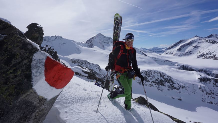 Auf Skitour steht Bergwanderführerin Elisabeth Götzinger mit Tourenskiern auf verschneitem Felsvorsprung.