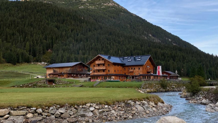 Blick auf das mehrstöckige Krimmler Tauernhaus mit traditioneller Holzfassade im Tal.