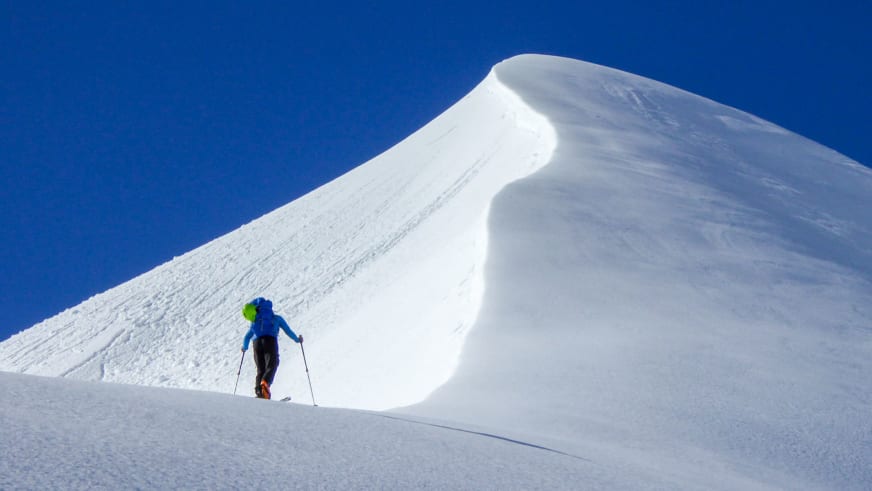 Auf Skitour steigt Bergführer Hermann Böhler einen steilen verschneiten Grat mit großer Schneewächte hinauf.
