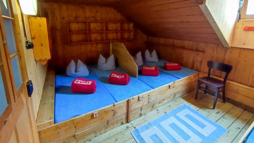 Innenraum eines Mehrbettzimmers in der Kaunergrathütte mit vier Einzelbetten und Holzausstattung.