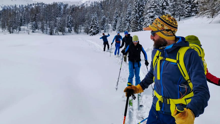 Fünf Skitourengeher bewegen sich durch Pulverschnee auf verschneiter Hochfläche, geführt von Bergführer Tommaso Cappelletto.