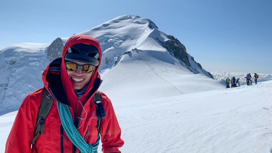 Bergführer José Salazar trägt rote Kapuzenjacke und gelbe Gletscherbrille auf schneebedecktem Gletscher mit Gruppe im Hintergrund.