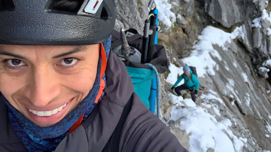 Selfie von Bergführer José Salazar mit Kletterhelm beim Klettern an schneebedeckter Kalksteinwand im Winter.