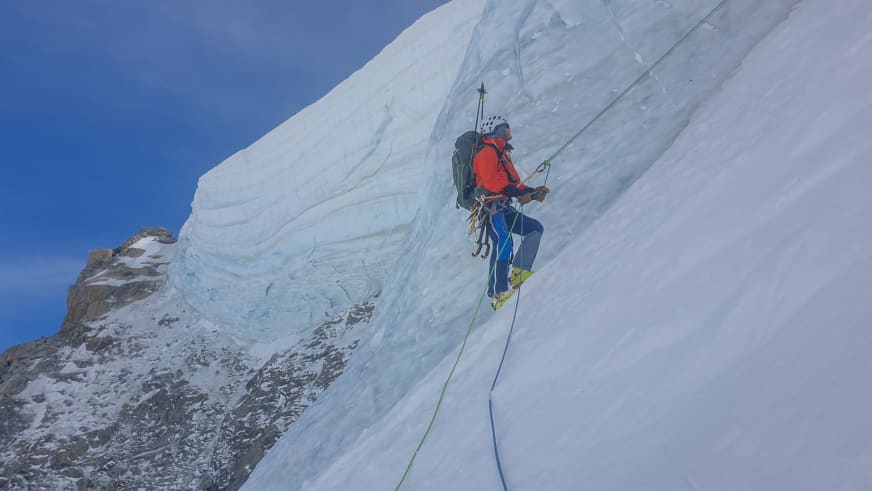 An steiler Eiswand seilt sich Bergwanderführer Christoph Knappe in roter Jacke und blauer Hose mit grünem Seil ab.