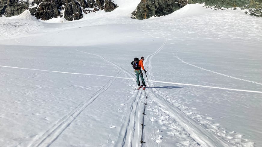 Zwei Skitourengeher steigen über einen Gletscher auf, Bergführer Simon Deckenbrock in oranger Jacke im Vordergrund.