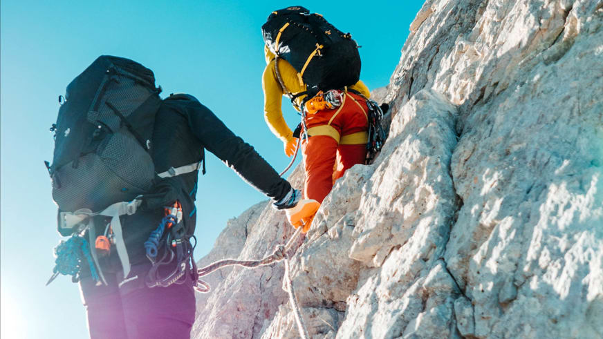 Zwei angeseilte Kletterer steigen an heller Kalksteinwand nach oben - Alpinklettern mit Bergführer Enrico Trapazzo.