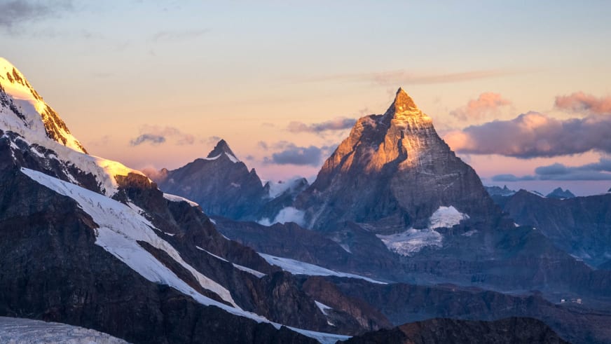 Panorama einer verschneiten Bergkette mit golden beleuchteten Gipfeln - Bergführer Enrico Trapazzo führt in dieser Region.