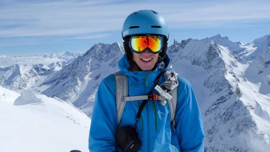 Portrait von Bergführer Fabian Bendlin mit blauem Skihelm vor schneebedecktem Hochgebirgspanorama.